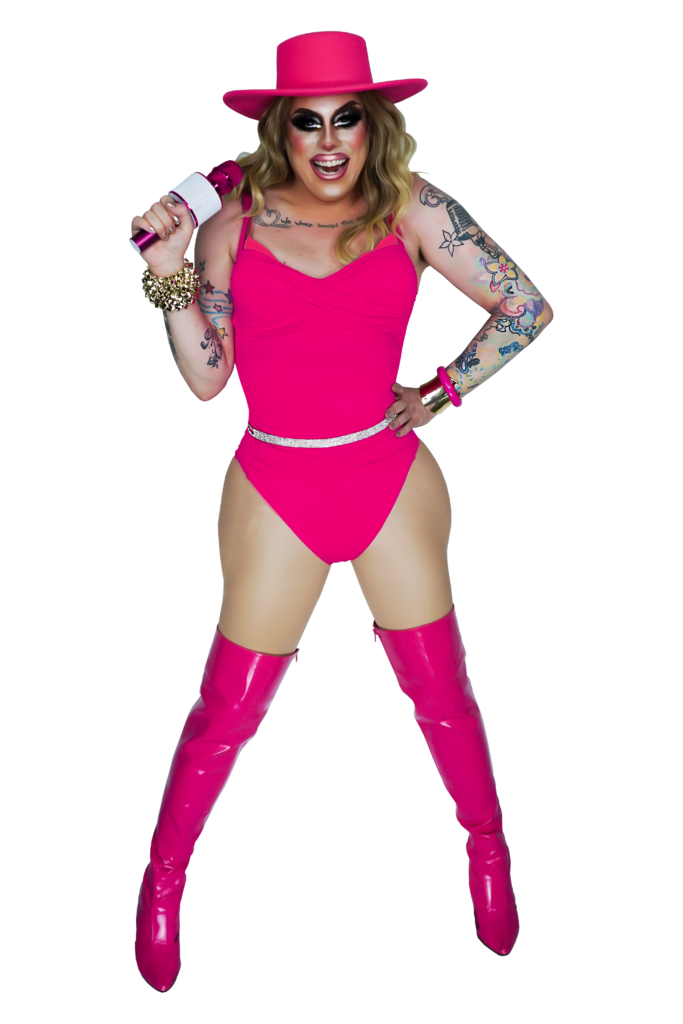A drag queen with light skin and tattoos, wearing an auburn wig, a hot pink bodysuit and thigh high boots
